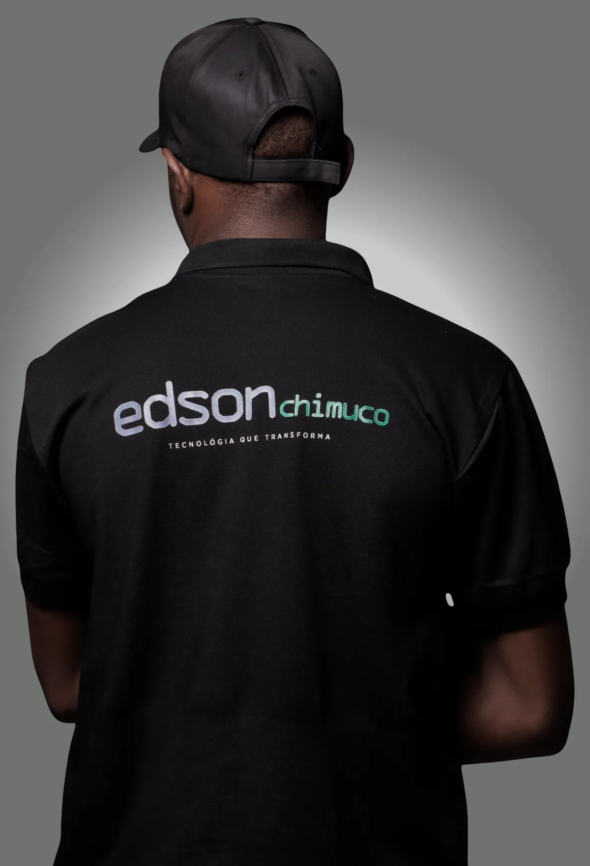 Costas de profissional com polo da marca Edson Chimuco e o lema Tecnologia que Transforma